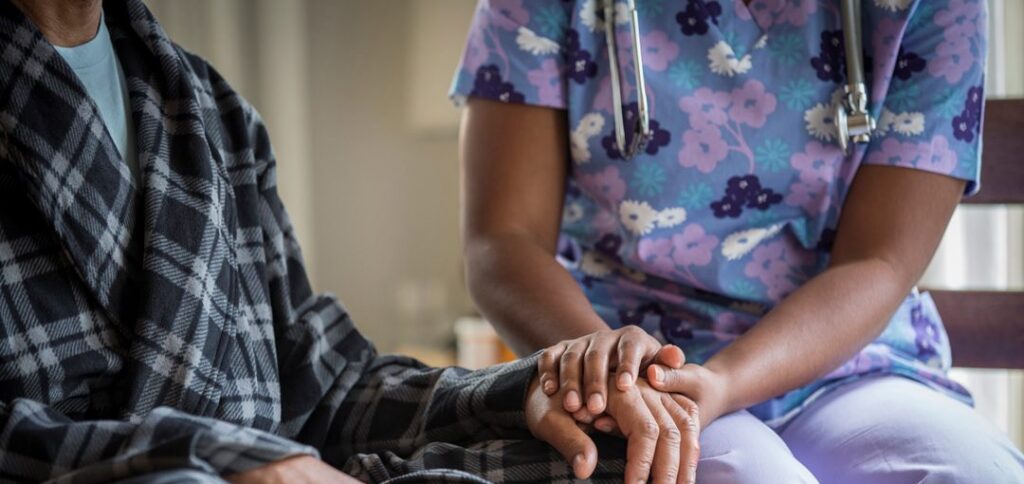 Care worker putting their hands on elderly person's hands